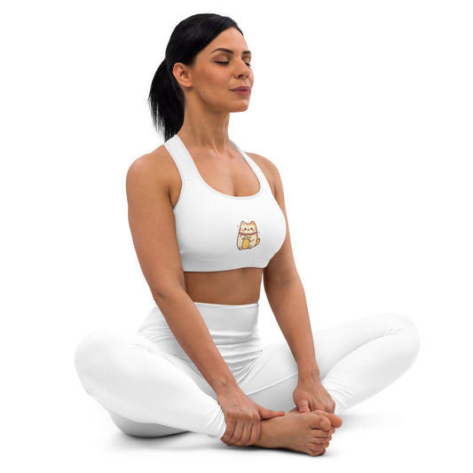 Woman in white 'Purely' sports bra and leggings sitting cross-legged on a white background