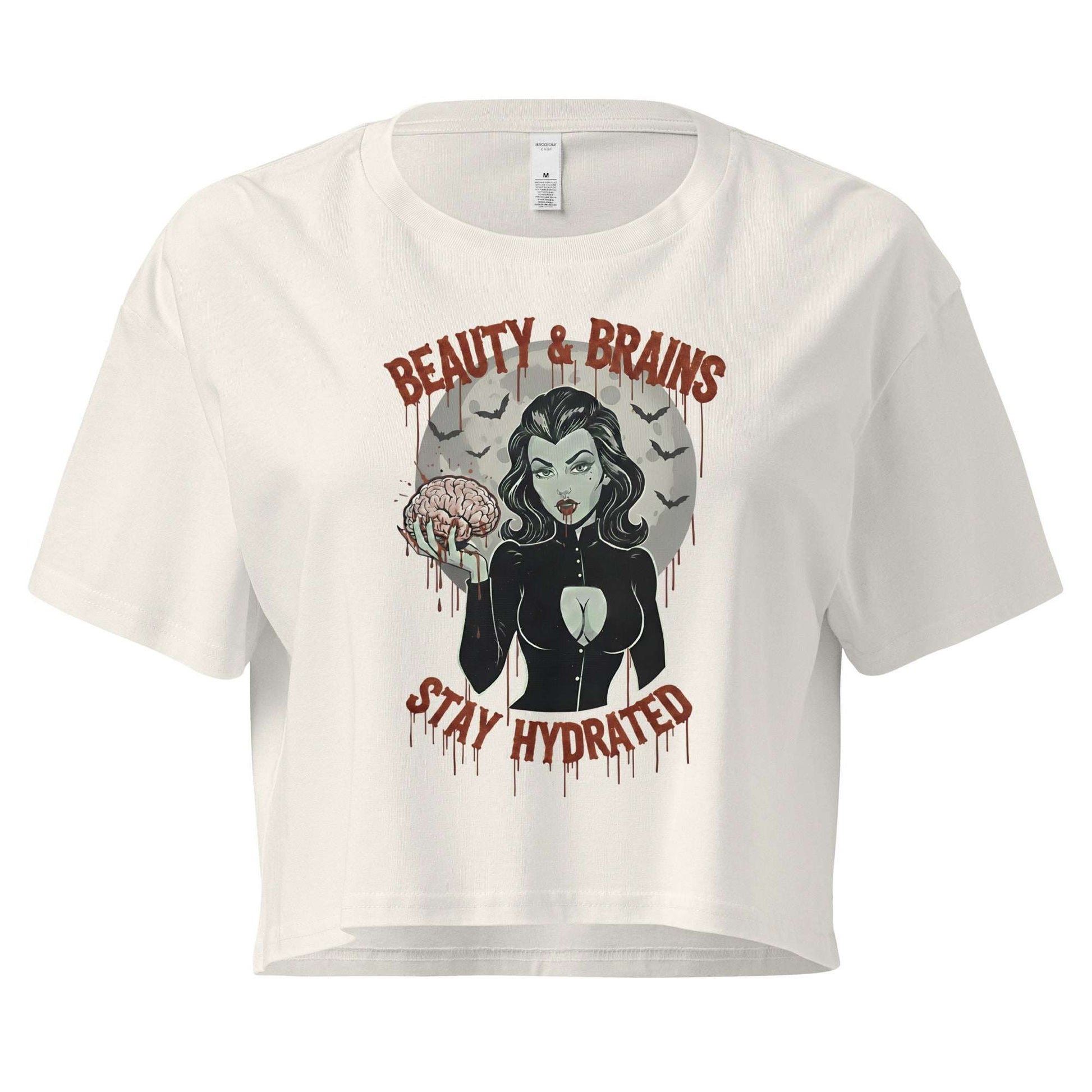 Women’s cream-colored loose crop top with Beauty & Brains gothic graphic and Stay Hydrated text.