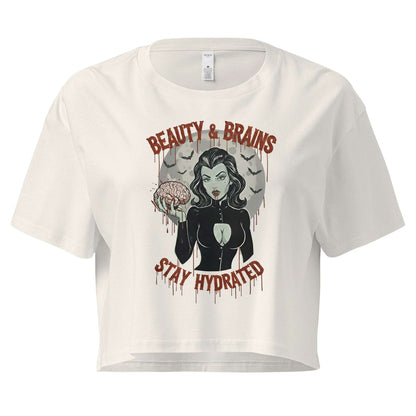 Women’s cream-colored loose crop top with Beauty & Brains gothic graphic and Stay Hydrated text.
