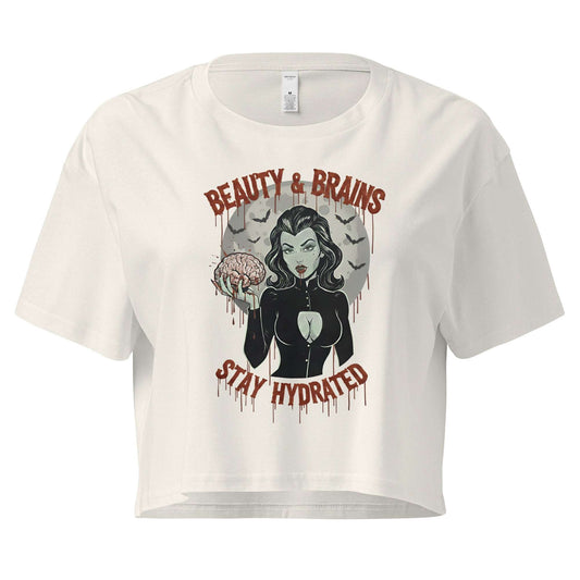 Women’s cream-colored loose crop top with Beauty & Brains gothic graphic and Stay Hydrated text.