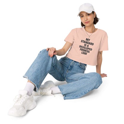 Person wearing a pink t-shirt with text and blue jeans sitting on a white background